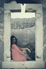 Close up of a 18Y old Girl Sitting in a Window of a Ruined House (location: Plemmirio Natural Park, Siracusa in Sicily)