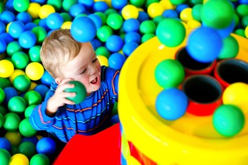 Fototapeta na wymiar Child excited by playing with colorful balls in playing centre