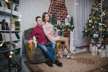 Young couple celebrating in the room decorated for Mary Christmas and New year