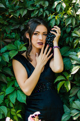 Portrait of young sexy brunette with black grapes.