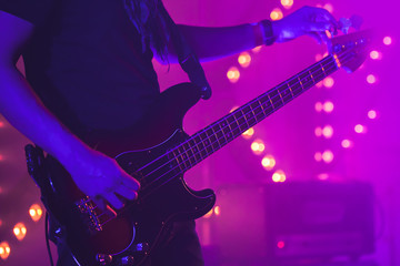 Obraz premium Guitarist tunes electric bass guitar