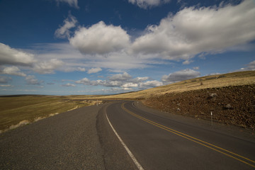 Naklejka premium winding road with cloudy blue sky