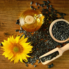 Seeds, oil and sunflower flower on a wooden background. Top view.