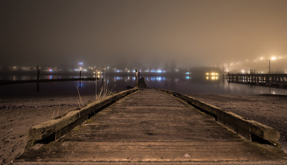 Obraz premium Long dock by the ocean on a foggy night