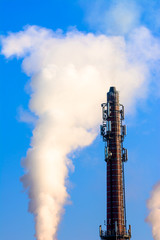 Power plant smokestack with carbon emission - co2, dioxide or fossil fuel. Air pollution by industry. Chimney and smoke cloud on blue sky background.