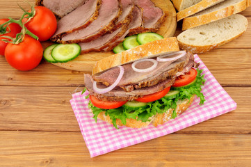 Roast beef salad sandwich with ingredients on a wood background