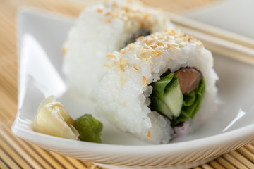 Zwei modern Style Inside Out Sushi mit Lachs, Rucola und Gurke mit Sojasoße und Holz Stäbchen