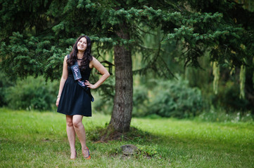 Portrait of gorgeous girl wear on black at hen party, posed at park.