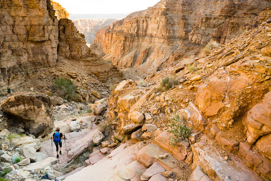A single adventurous female hiker, trekking down into a steep, rocky canyon while hiking into the Fish River Canyon in Namibia