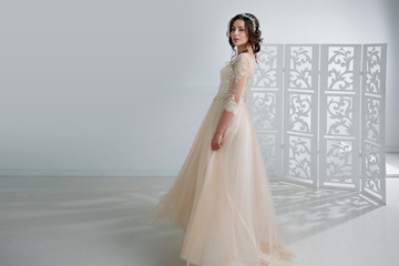 Fototapeta na wymiar Portrait of a beautiful girl in a wedding dress. Bride in a luxurious dress, in a beautiful white interior