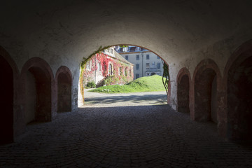 Durchblick durch die dunkle Einfahrtshalle auf den Innenhof und die mit herbstlich roten Blättern bedechte Fassade des Neuen Schloss' von Baden-Baden, Baden-Württemberg, Deutschland