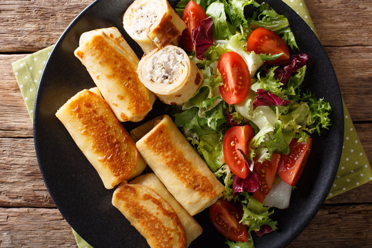 crepes rolls with chicken, cheese and mushrooms close-up and vegetable salad. Horizontal top view