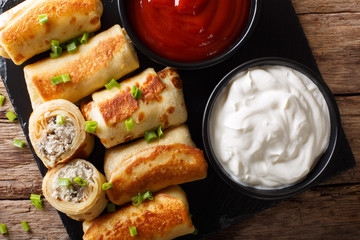 Crepes with chicken and mushrooms close-up and tomato sauce, sour cream. Horizontal top view