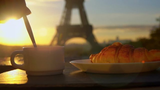 Cup of coffee with a croissant on a sunny morning in the background of the Eiffel Tower