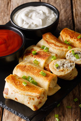 Crepes stuffed with chicken and mushrooms close-up and tomato sauce, sour cream. vertical