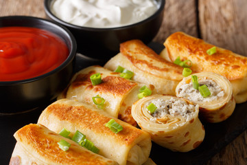 Crepes with chicken and mushrooms close-up and tomato sauce, sour cream. Horizontal