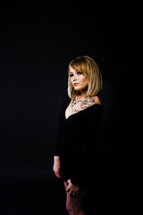 Studio portrait of blonde girl with originally make up on neck, wear on black dress at dark background.