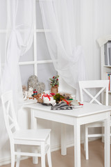 white room interior with christmas decoration, window, table and chair