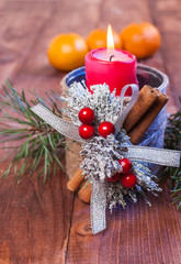Candle, spruce branches and mandarins on a wooden background