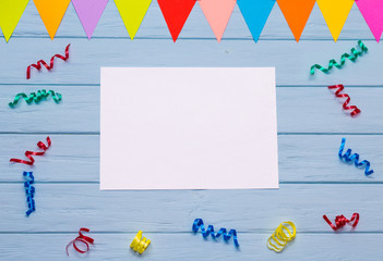 White blank paper with colorful ribbons around on blue wooden table. Office composition