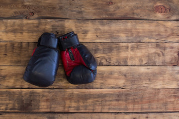 Old Black Boxing Gloves on  Vintage Wooden Grunge Background Copy Space.