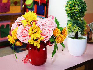 Artificial rose flowers in red vase