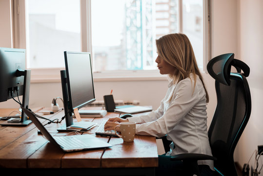Image of busy woman working on computer in office.