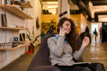 Attractive young woman in modern interior talking on phone.