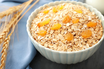 Bowl with oatmeal flakes and raisins on table, closeup