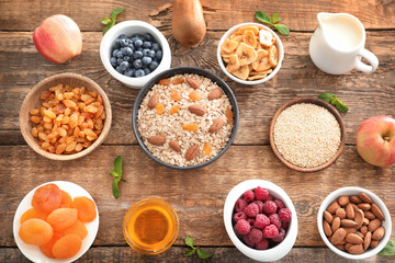 Oatmeal flakes and many different toppings on wooden background