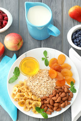 Plate with oatmeal flakes and toppings on wooden background