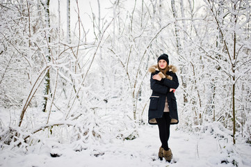 Beautiful brunette girl in winter warm clothing. Model on winter jacket and black hat.