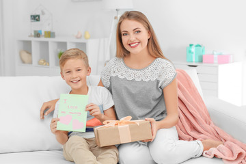 Young woman with her little son and Mother's Day gift at home