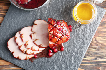 Slate plate with traditional honey baked ham and cranberry sauce on table