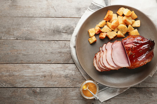 Plate with traditional sliced honey baked ham and potatoes on table