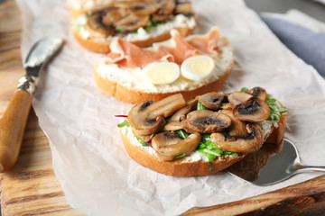 Tasty toast with mushrooms on board, closeup