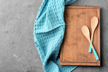 Clean kitchen towel, board and spoons on grey background, top view