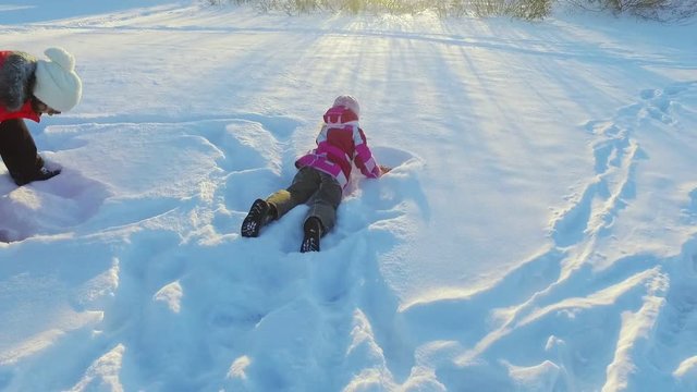 Mother playing snow with daughter in slow motion. Happy winter rest. Family have fun in sunny winter day