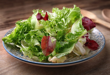 Plate with fresh salad on table