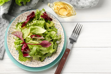 Plate with fresh salad on white wooden table