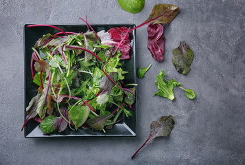 Plate with fresh salad on grey table, top view
