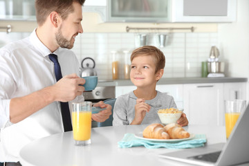 Obraz na płótnie Canvas Father with son having breakfast in kitchen