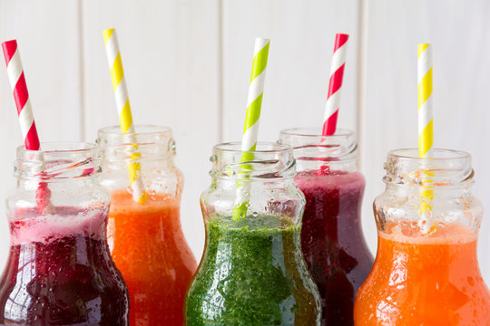 Detox drinks in bottles: fresh smoothies from vegetables: beet, carrot, spinach, cucumber and apple on white background