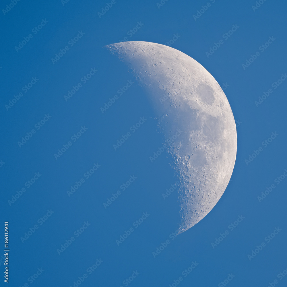 Wall mural moon - waxing crescent against blue sky background