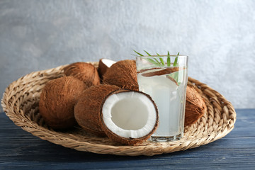 Glass of coconut water with nuts on wicker tray