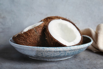 Plate with fresh coconuts on grey background