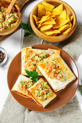 Traditional Mexican dish - chimichanga. Corn cake with minced meat, pepper, onion, garlic, oregano, zira and guacomole sauce from avocado.