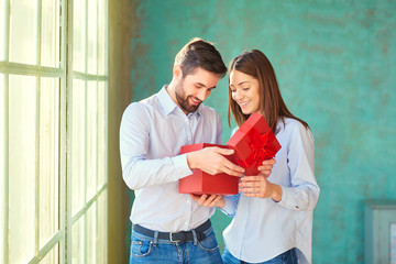 The guy gives a gift box to his girlfriend. Young couple on holiday. St. Valentine's Day.