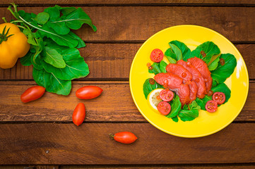 Fresh salmon with lemons and spinach on a wooden rustic background. Top view. Selective focus
