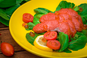 Fresh salmon with lemons and spinach on a wooden rustic background. Top view. Selective focus